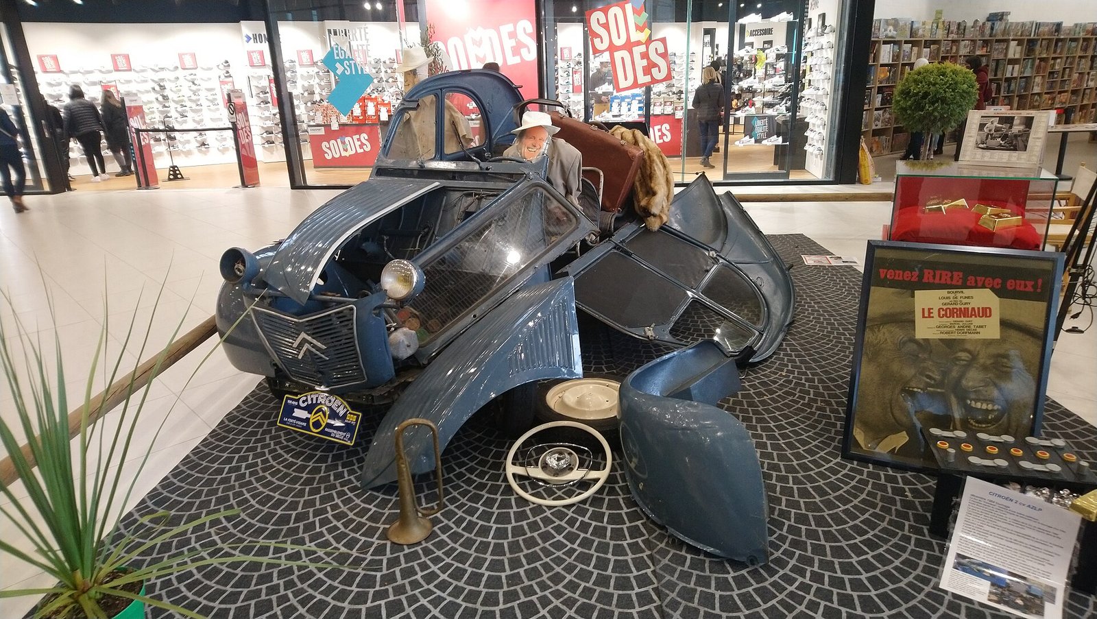 2CV grise disloquée présentée dans une exposition consacrée au Corniaud